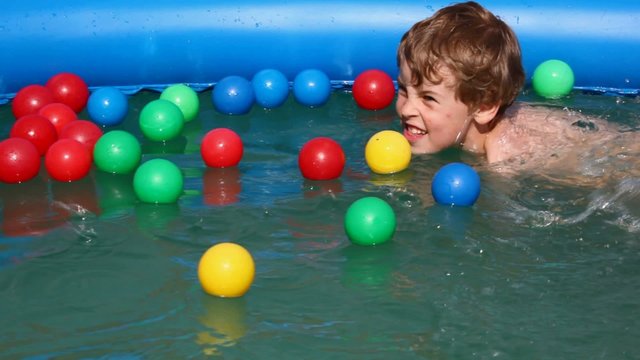 boy swimming after colorful balls