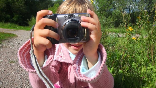 portrait of little girl with photo camera in park
