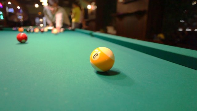 man in billiards shoots yellow ball in pocket