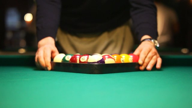 man collect balls in triangle on biliards table