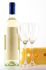Bottle of white wine and two empty wine glasses and cheese