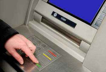 Cash withdrawal. Woman's hand entering pin on ATM