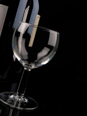 Empty wine glass in front of a wine bottle. close up