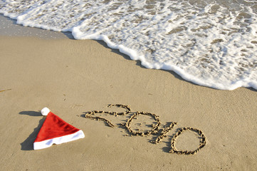 Santa hat with New Year on the sand with wave.