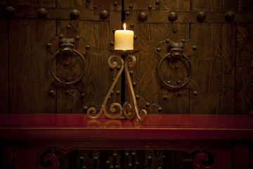 Candles burning on table in front of old rustic door