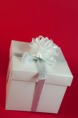 pacco regalo con nastro argentato su fondo rosso