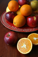Apples and oranges on a red plate