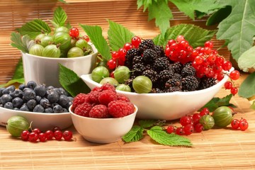 Berries in plates, on a table, among green leaves