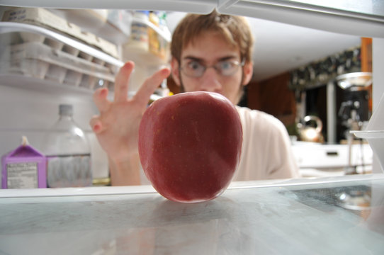 Man snatching apple from fridge