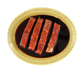 Several steak strips marinating in balsamic vinegar