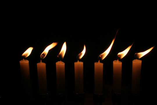 sieben Kerzen mit unruhiger Flamme