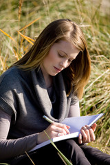 Frau schreibt Tagebuch am Strand