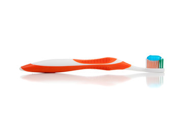 An orange toothbrush with paste on white