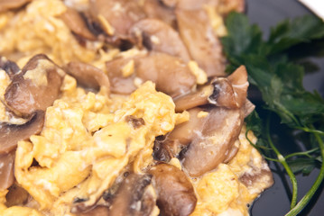 scrambled eggs with champignon mushrooms on frying pan