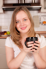 Young happy woman drink morning coffee in kitchen