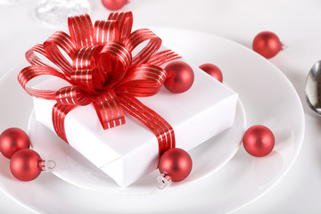 White present with red ribbons on plate, christmas theme