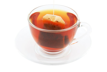 Glass cup of hot tea on plate with tea bag isolated