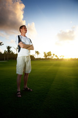 young man on green field and sunset