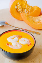 Bowl of warm pumpkin soup decorated with prawns