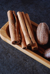Whole cinnamon sticks and nutmeg in a wooden dish