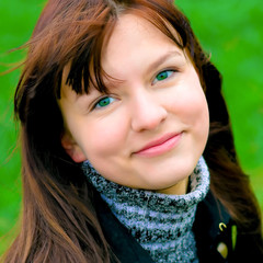 portrait of the beautiful smiling girl over green field