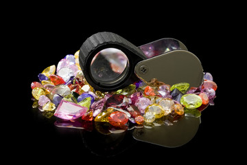 A jewelers loupe resting on a small treasure of gems