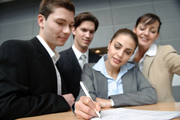 gesch&auml;ftsfrau unterschreibt mit team hinter sich vertrag