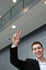 geschäftsmann steht in büro und jubelt mit victoryzeichen