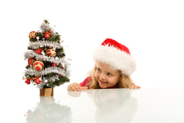 Happy kid lurking around a small christmas tree