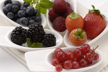 Assorted berries in white  spoons.
