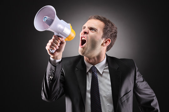Angry businessman announcing via loudspeaker