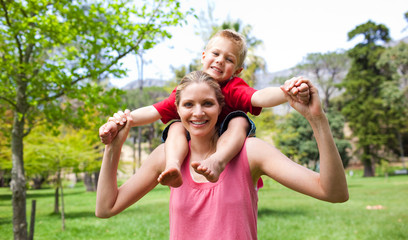 Happy mother giving her son a piggyback ride