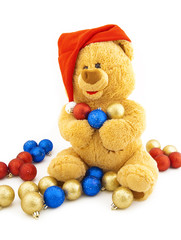 Toy bear in a Christmas cap and with Christmas-tree decorations