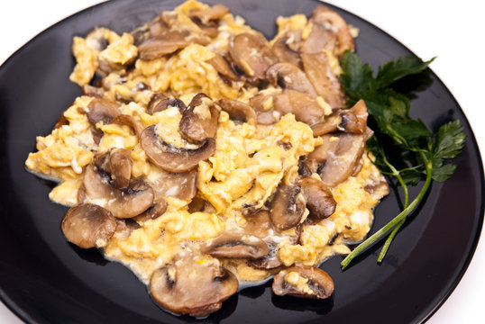 scrambled eggs with champignon mushrooms on frying pan