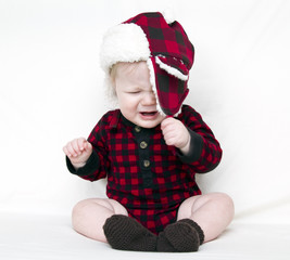 Crying Christmas baby trying to pull off fuzzy hat
