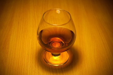 glass of cognac close-up on wooden background