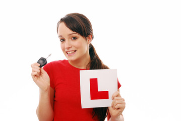 Teenager holding car key and L plate after passing driving test