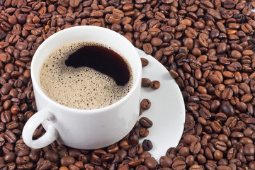 cup of coffee over a lot of coffee beans