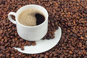 cup of coffee over a lot of coffee beans