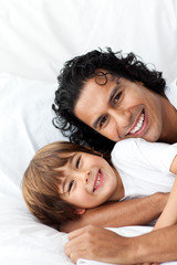 Smiling father and his little boy lying on the bed