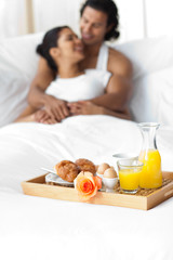 Obraz na płótnie Canvas Smiling lovers having breakfast on the bed
