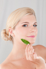 Young healthy woman with pure skin and green plant