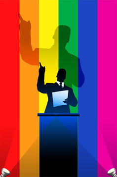 Gay Pride flag with political speaker behind a podium