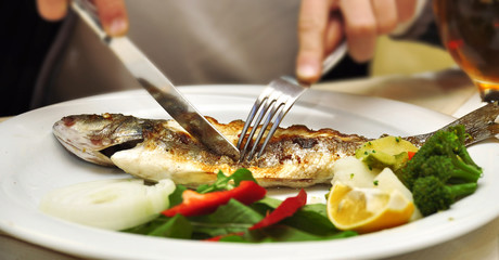 Fried fish with a lemon on a white dish
