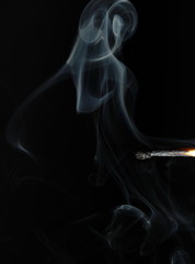 Rauchendes Z&uuml;ndholz vor schwarzem Hintergrund