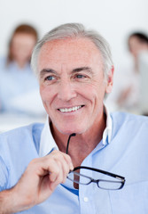 Smiling senior businessman holding glasses