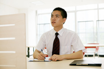 young asian businessman sitting on desk in office