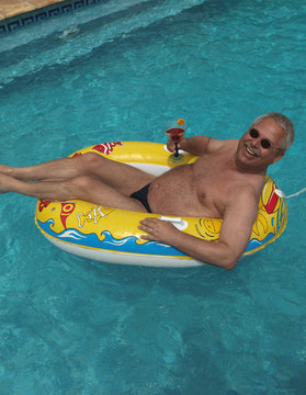 &auml;lterer Mann im Urlaub, Swimmingpool, Schlauchboot
