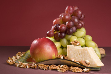 Fruits and cheese lying in a plate.