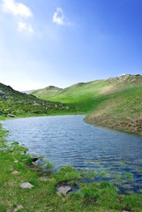 small blue lake in a green hills
